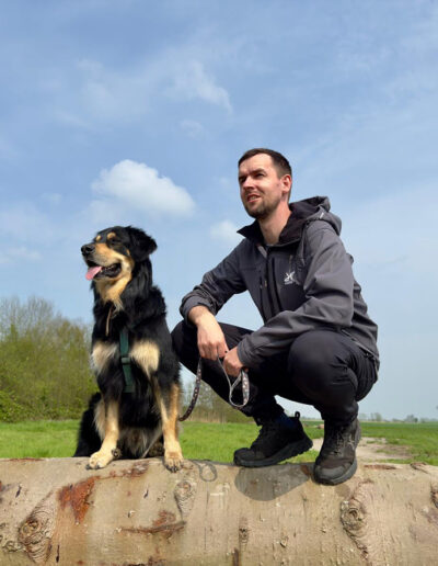 Hund und Besitzer sitzen auf Baumstamm