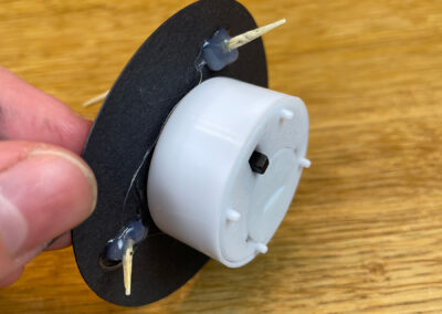 Zahnstocher mit Heißklebepistole von unten an schwarzem Kreis befestigen