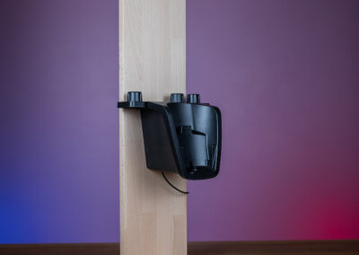 Ein Akkusauger hängt stabil an einem Holzständer, der frei an einer Wand lehnt.